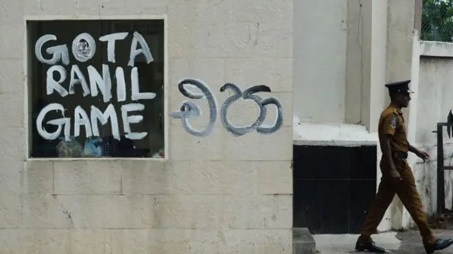 A policeman walks past slogans painted on a wall against the newly elected Sri Lankan President Ranil Wickramasinghe, near the presidents office residence in Colombo on July 21, 2022