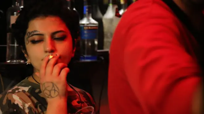 Universitetdəki dərsdən sonra barda içki satan gənc qız işə fasilə verib siqaret çəkir.