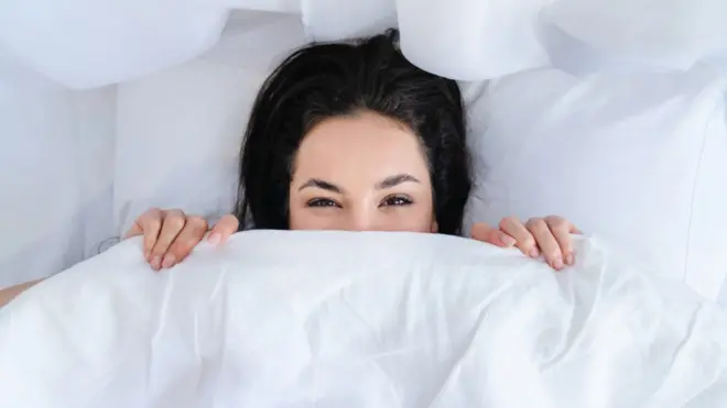 Una mujer debajo de las sábanas