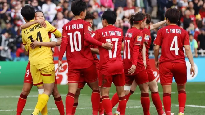 Vietnam keeper Tran Thi Kim Thanh is mobbed by her jubilant team-mates after saving Alex Morgan's penalty