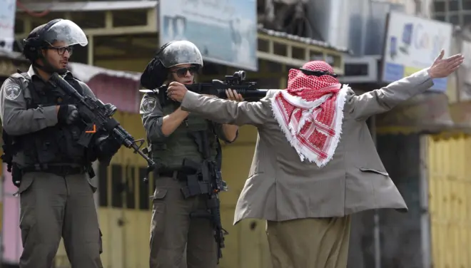 الشيخ زياد أبو هليل يمنع شرطي إسرائيلي من إطلاق النار على المتظاهرين خلال اشتباكات في مدينة الخليل بالضفة الغربية المحتلة في 10 أكتوبر/تشرين الأول 2015