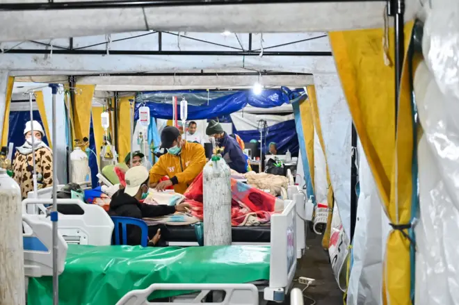 Keluarga menunggu pasien yang menjalani perawatan di tenda darurat.
