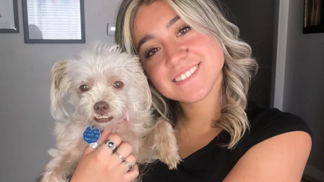 Caroline Dias Gonçalves, uma jovem loira e sorridente, segurando um cachorrinho