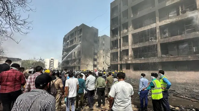 Varias personas en una zona cercana al lugar del accidente, en donde se ven edificios que estuvieron incendiados