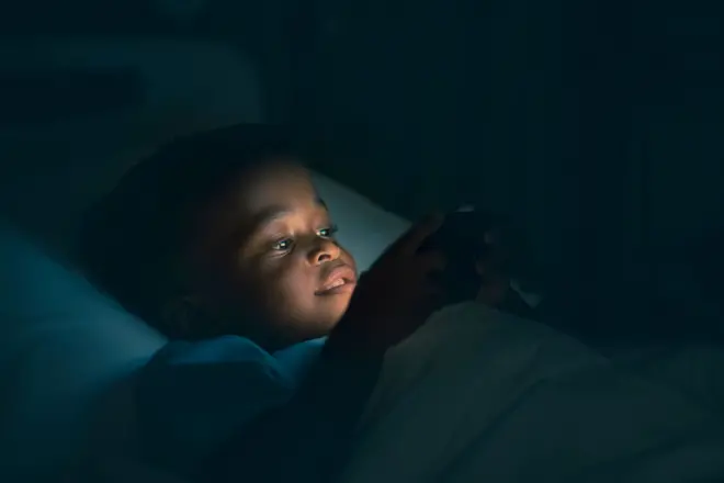 Garçon utilisant un téléphone dans la pénombre