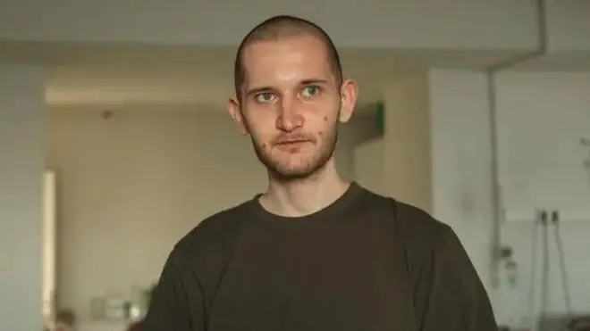 Јуриј Гулчук у маслинасто зеленом дуксу ошишан до главе, портретна фотографија