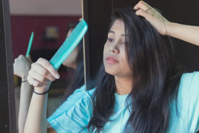 Indian young Frustrated girl holds comb with her hair fell out. indoor shoot at home.
