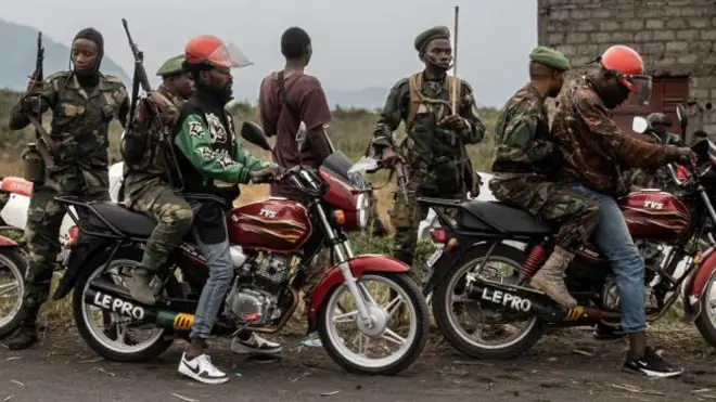 Des motos-taxis conduisent des miliciens Wazalendo (Patriotes en swahili), qui font partie d'un groupe de milices pro-gouvernementales, le long de la route menant à l'entrée de la ville de Sake, à 25 km au nord-ouest de Goma, le 23 janvier 2025. 