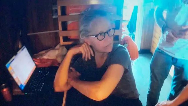 Wendy Rush, woman wey wear grey t-shirt, look away from di laptop with an anxious expression