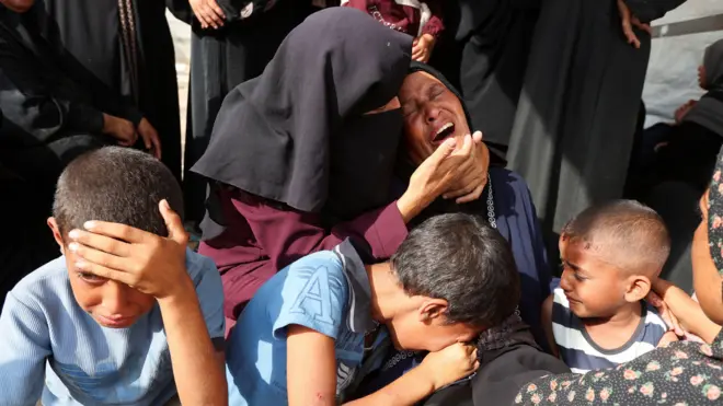 سيدات وأطفال يبكون خلال تشييع جنازة من قُتلوا في الغارات الإسرائيلية في مستشفى ناصر في خان يونس، جنوب قطاع غزة، 12 يوليو/تموز 2025.