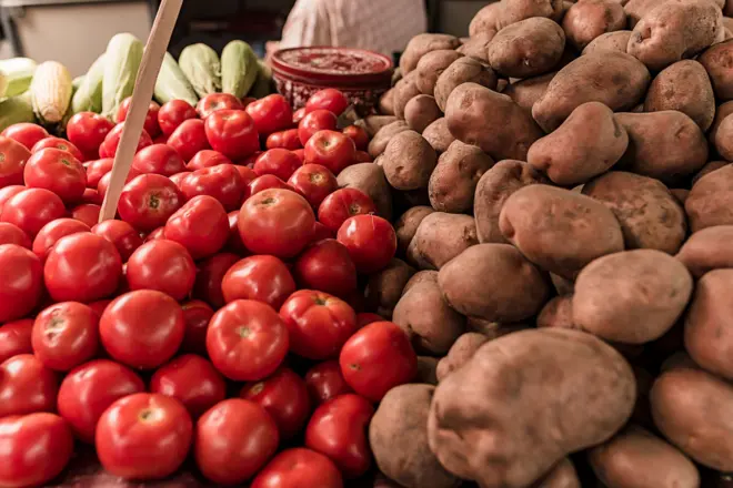 Close-up view of tomatoes and potatoes laid out at a farmers market