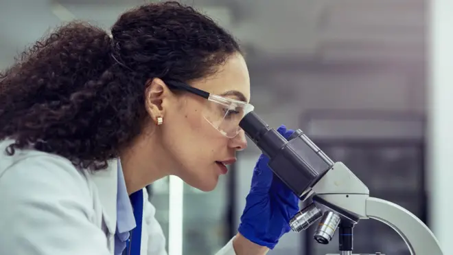 Científica mira por el microscopio. 