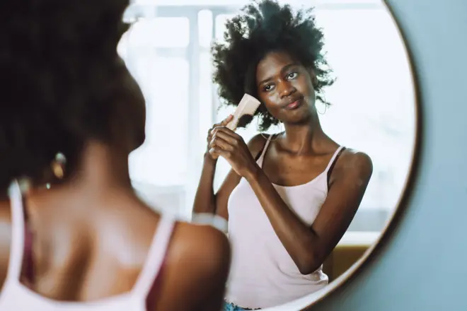 Femme se peignant les cheveux devant un miroir