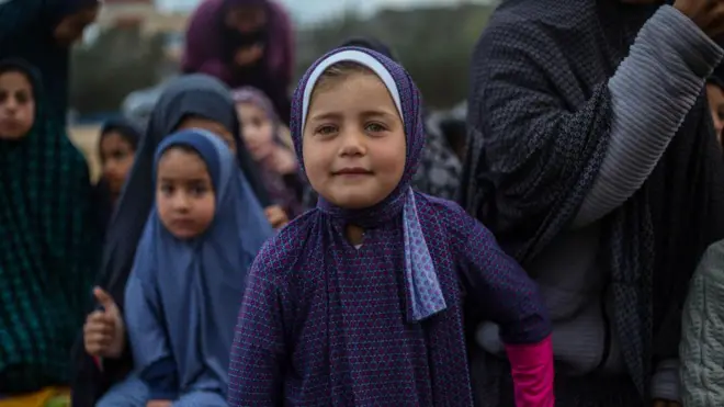 فتاة صغيرة ترتدي ملابس صلاة.