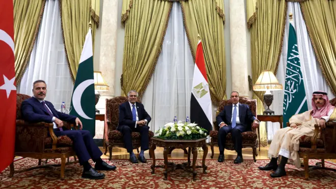 Hakan Fidan ve Pakistan, Mısır ve Suudi Arabistanlı mevkidaşları Kahire toplantısında koltuklarda oturmuş halde ve her bir ülkenin bayrağı önünde poz veriyor
