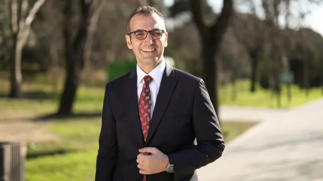 Resul Emrah Şahan bir parkta takım elbiseyle poz veriyor