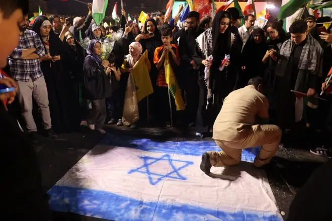 Em foto noturna, homem aparece ajoelhadocomo ganhar na aposta esportivabandeiracomo ganhar na aposta esportivaIsrael, observado por várias pessoas