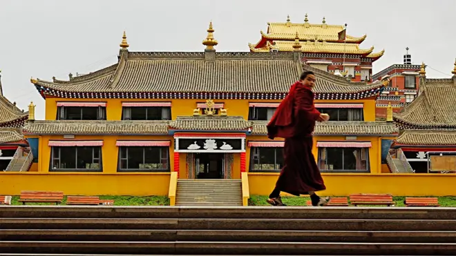 A monk walks across a courtyard at Langcuo Ma Monastery