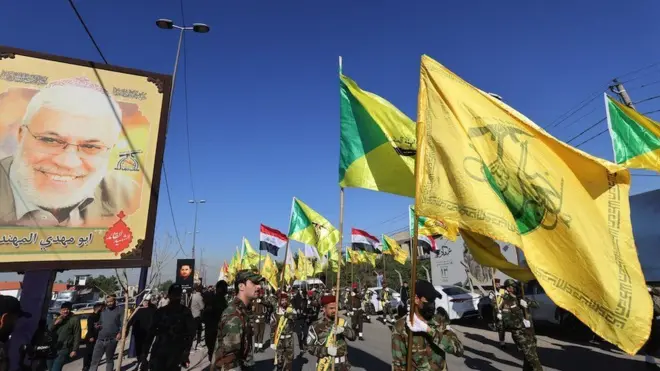 Fighters lift flags of Iraq and paramilitary groups, including al-Nujaba and Kataib Hezbollah, during a funeral in Baghdad for five militants killed a day earlier in a US strike in northern Iraq, on 23 December 2023