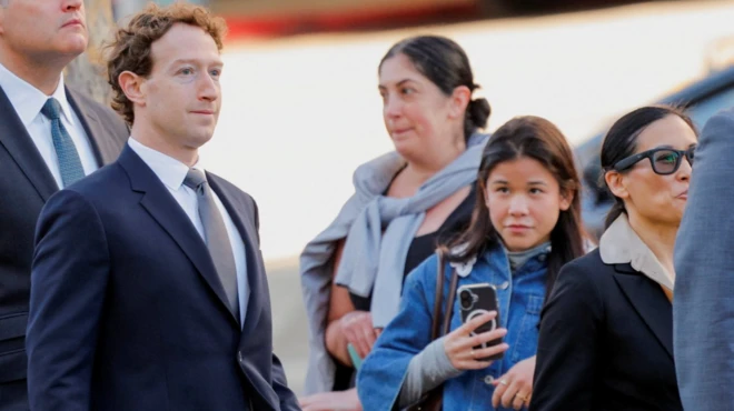 Takım elbiseli Zuckerberg, ilgili halkın bakışları arasında dışarıda yürüyor. 