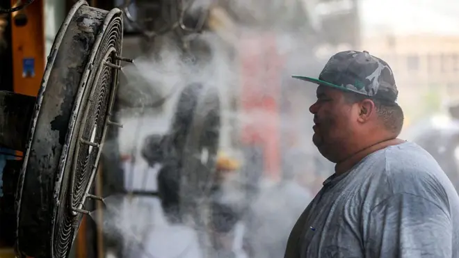 巴格達氣溫飆升至50攝氏度以上，一名男子站在一台噴水的風扇前。