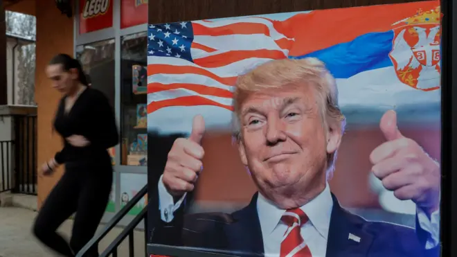 Девојка у Северној Митровици пролази поред постера са Доналдом Трампом и заставама Србије и Сједињених Америчких Држава