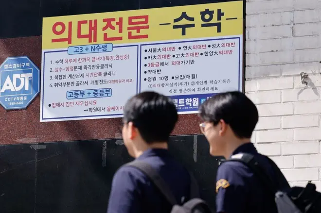 두 학생이 학원 간판이 걸린 거리를 걷고 있다