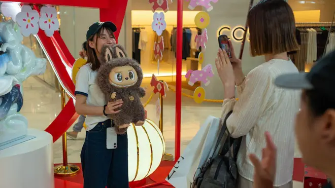 Uma jovem tira fotos com um brinquedo Labubu na loja pop-up