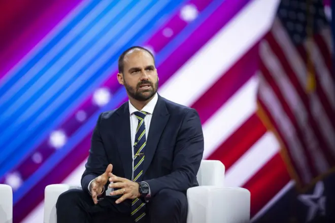 Eduardo Bolsonaro com bandeira americano no fundo