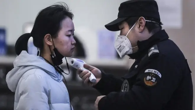 Petugas memeriksa suhu tubuh penumpang di kapal penyeberangan di Sungai Yangtze di Wuhan.