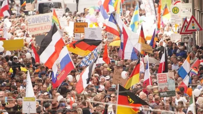 Para demonstran memegang bendera Jerman, Rusia, Belanda, Kekaisaran Jerman, dan Bavaria