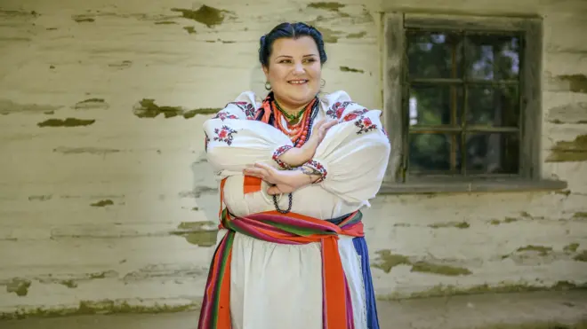 Альона Альона і стрій з Кіровоградщини- початок ХХ ст. На співачці - сорочка святкова. Спідниця, оздоблена оксамитовою стрічкою. Пояс "Веселка", широкий виготовлений з тонкої вовняної нитки, фартух білий сатиновий, вишитий, оздоблений мереживом, намисто коралове, перли, дукач латунний, сережки срібні "Бублички"