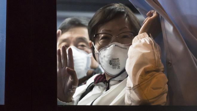 一名搭乘大巴前往东京羽田机场登上美国撤侨包机的钻石公主号女乘客向车外记者挥手（16/2/2020）