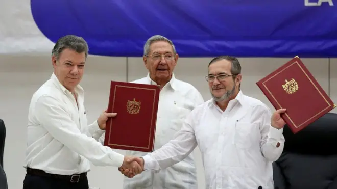 O presidente colombiano, Juan Manuel Santos (esq.) e o líder das Farc, Timochenko (dir.), assinaram o acordosport 2Havana, com a participação do presidente cubano, Raúl Castro (centro)