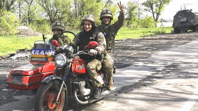 Ukrainian servicemen ride a motorcycle on the road which connects Kharkiv and a village recently retook by the Ukrainian Army