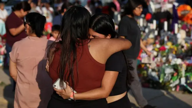 Women embrace at a memorial to those killed in the Uvalde mass shooting