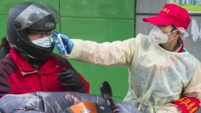 武漢市社區工作人員為進小區者量體溫。
