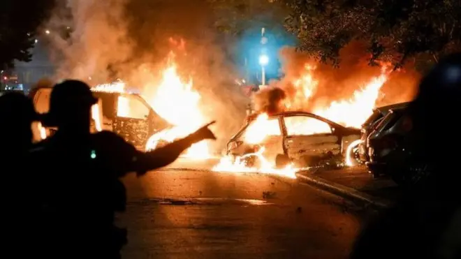 Police officers stand near burning cars during protests in Nanterre, west of Paris, on June 28, 2023, a day after the killing of a 17-year-old boy in Nanterre by a police officer's gunshot