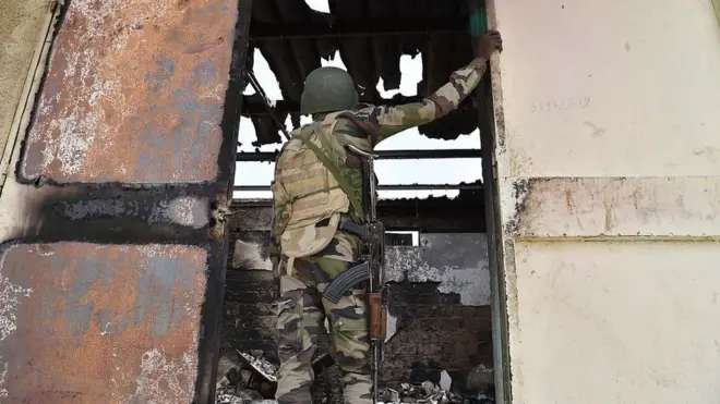 Soldier wey stand dey look area wey bomb don scatter.