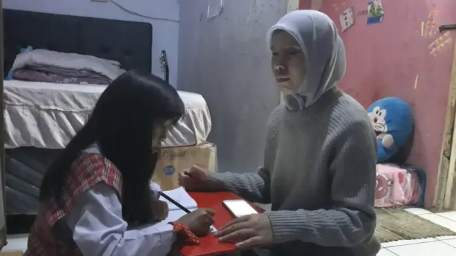 Popon mendampingi anaknya belajar secara daring.