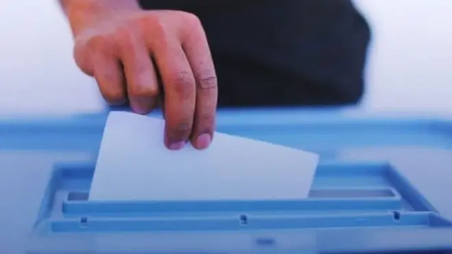 ድምጽ የሚሰጥ ሰው እጅ እና የድምጽ መስጫ ሳጥን