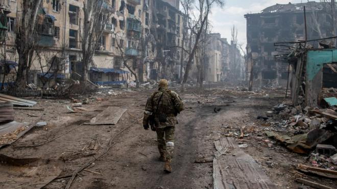 A Russian soldier walks amidst the rubble in Mariupol's eastern side