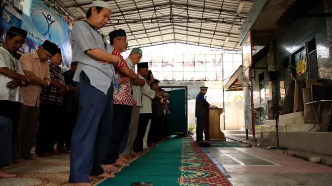 Jemaah Ahmadiyah melakukan salat Jumat di halaman belakang masjid, sementara masjidnya kosong.