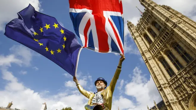 мужчина держит флаги ес и британии