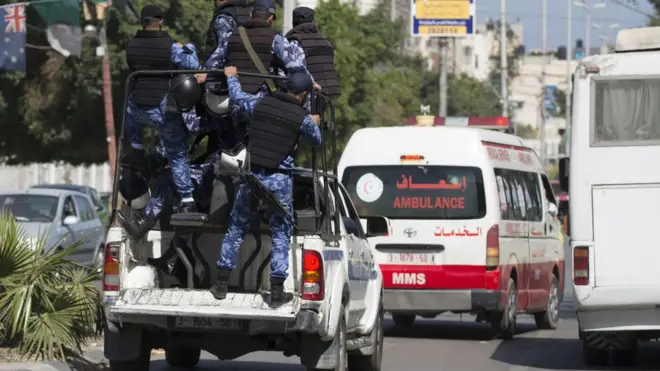 Aparat keamanan mengawal ambulans yang membawa jenazah tiga warga Palestina yang digantung oleh Hamas.