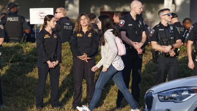 警察や事件を悼む人々に見守られながら、マージョリー・ストーンマン・ダグラス高校の教職員と生徒は学校に戻ってきた。=2018年2月28日、米フロリダ州パークランド