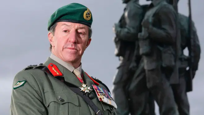 Gen Sir Gwyn Jenkins, in military uniform with medals on his chest, standing in front of the Commando Memorial in Locharber in the Scottish Highlands