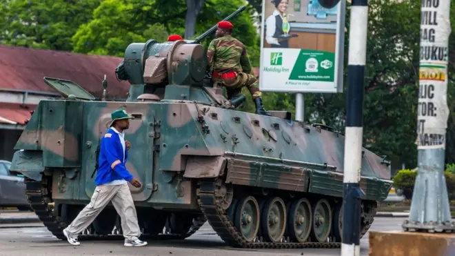 A man walks past an armoured personnel carrier in Harare on November 15, 2017