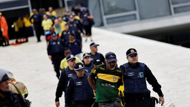 Fotografia colorida mostra homem sendo levado pela policia federal