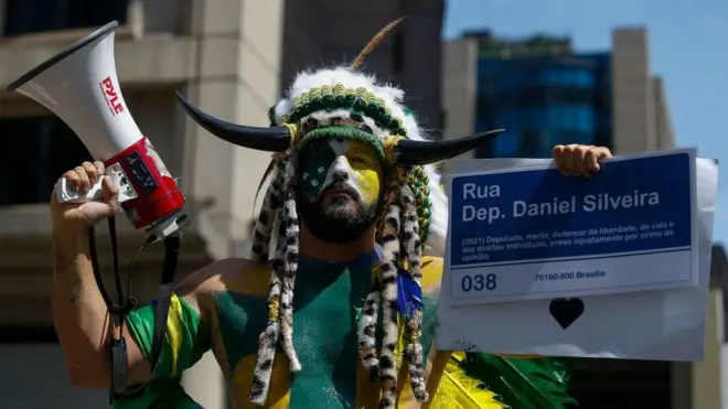 Сторонник Трампа и теорий заговора Джейк Анджели, которого копировал этот бразильский сторонник Болсонару на митинге во вторник, всего пять дней назад признал в суде вину в нападении на Капитолий